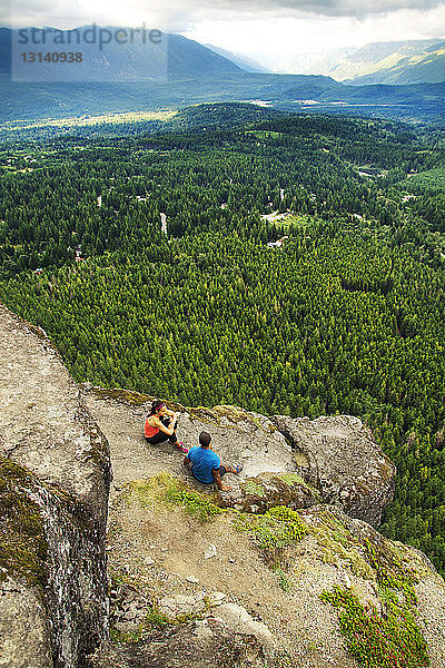 Hochwinkelansicht eines auf einem Bergfelsen sitzenden Paares