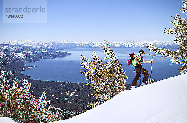 Seitenansicht eines Skifahrers  der auf einem schneebedeckten Berg vor klarem Himmel läuft