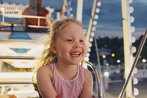 Glückliches Mädchen sitzt im Riesenrad im Vergnügungspark