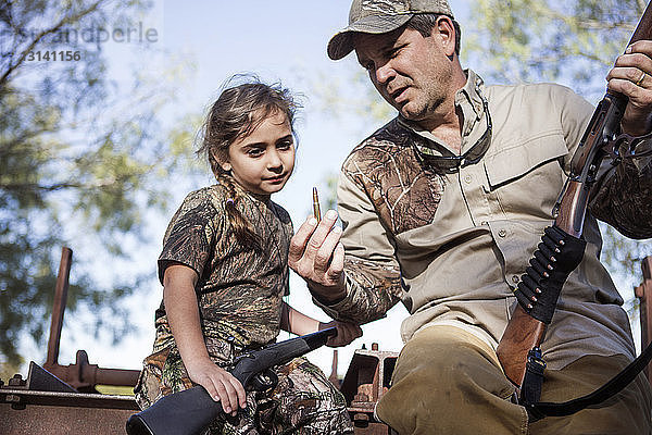 Mann erklärt seiner Tochter eine Kugel  während er auf einer Maschine sitzt