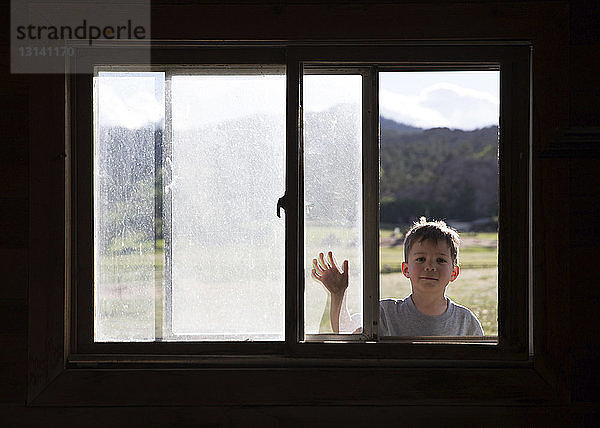 Porträt eines Jungen  der durch ein Fenster schaut