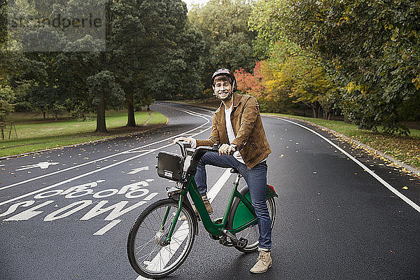 Porträt eines glücklichen Mannes mit Fahrrad auf der Strasse im Park