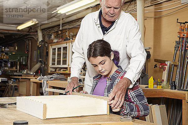 Zimmermann hilft Mädchen bei der Herstellung eines Holzregals