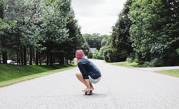 Seitenansicht einer Frau  die auf einem Skateboard kauert