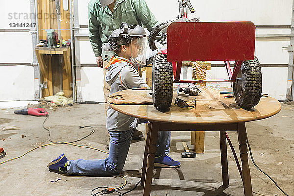 Vater assistiert dem Sohn beim Bau eines Dreirads in der Werkstatt