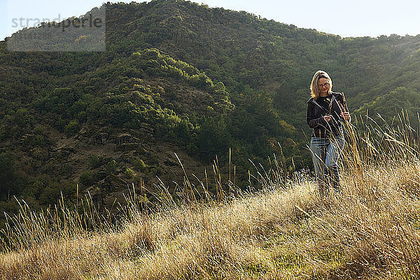 Frau hält Stock  während sie auf dem Berg steht