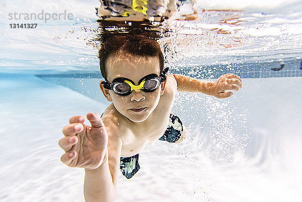 Porträt eines Jungen ohne Hemd  der im Schwimmbad unter Wasser schwimmt