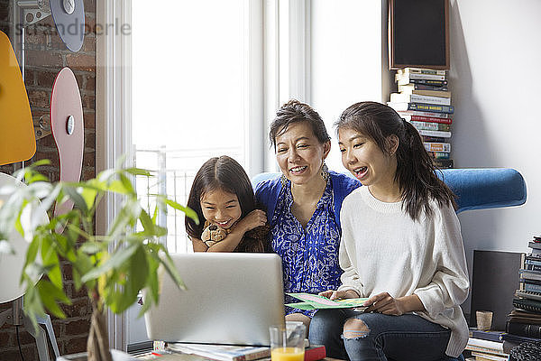 Fröhliche Mutter und Töchter bei Videoanrufen mit Laptop zu Hause