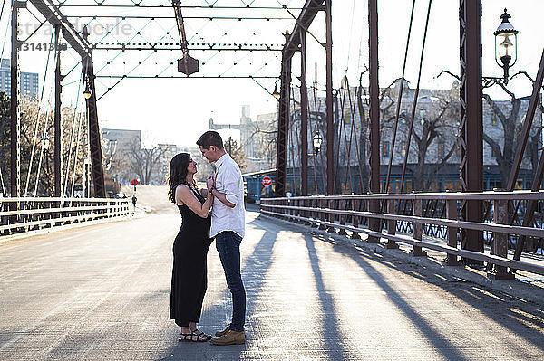 Seitenansicht eines romantischen Paares  das sich auf einer Brücke gegen den klaren Himmel anschaut