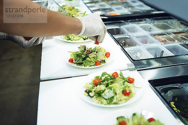 Ausgeschnittenes Bild eines Küchenchefs  der Essen in einer Großküche serviert