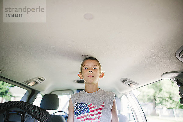 Niedrigwinkel-Porträt eines selbstbewussten Jungen  der im Auto steht