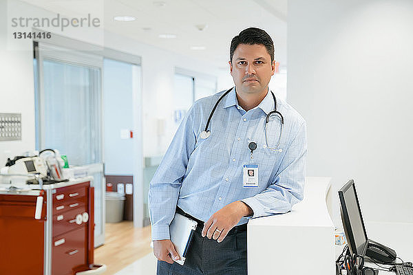 Porträt eines selbstbewussten Arztes mit Tablet-Computer am Krankenhausempfang stehend