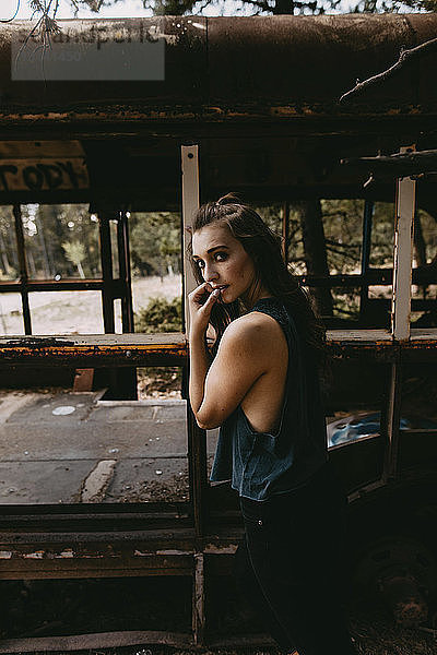 Porträt einer selbstbewussten jungen Frau  die an einem verlassenen Fahrzeug steht