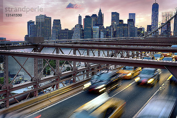 Autos bewegen sich bei Sonnenuntergang auf der Brooklyn Bridge