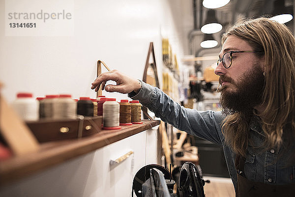 Schuster wählt Spule im Regal beim Workshop