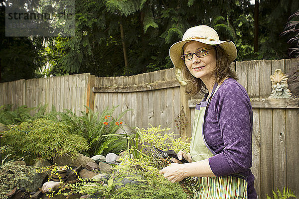 Porträt einer Frau  die eine Gartenschere hält  während sie im Hinterhof steht