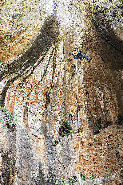 Niedrigwinkelansicht eines Mannes  der sich vom Felsen abseilt