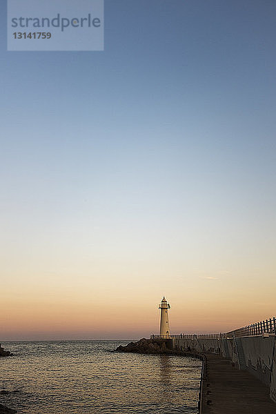 Leuchtturm auf der Seebrücke vor blauem Himmel bei Sonnenuntergang