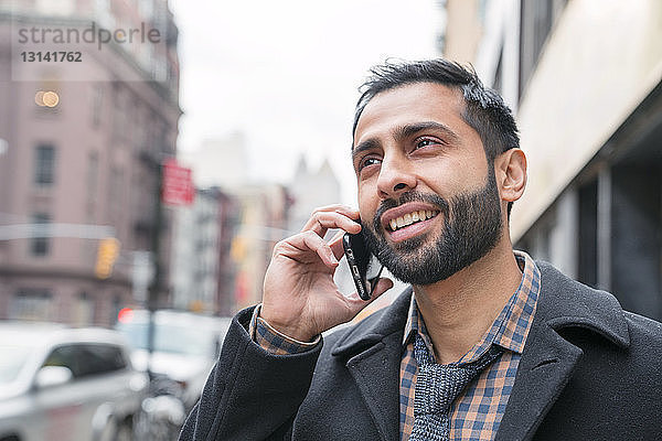 Geschäftsmann spricht mit einem Smartphone  während er in der Stadt steht
