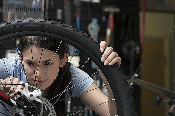 Frau repariert Fahrradbremse in Werkstatt