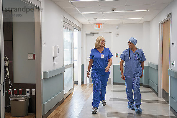 Chirurg und Krankenschwester sprechen während des Gehens im Krankenhauskorridor