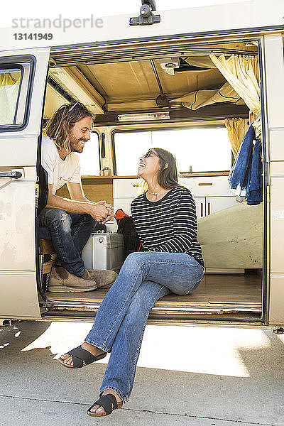 Glückliches Paar unterhält sich während des Urlaubs im Mini-Van