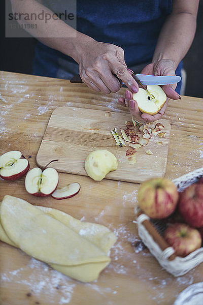 Geschnittene Hände einer Frau  die Äpfel für die Zubereitung von Zimtbrötchen zu Hause schneidet