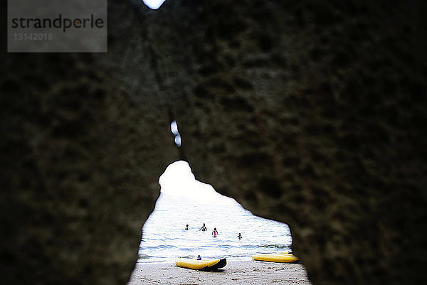 Familie genießt am Strand durch Felsen gesehen