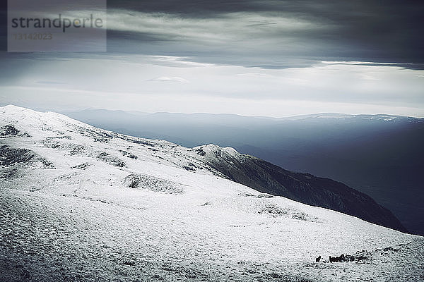 Landschaftliche Ansicht der Berge vor bewölktem Himmel im Winter