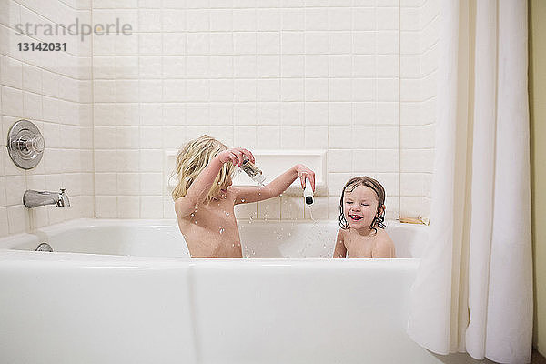 Schwestern ohne Hemd spielen beim Baden in der Badewanne zu Hause