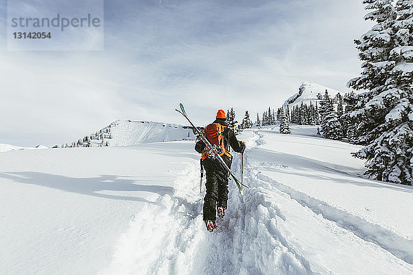 Rückansicht eines Wanderers mit Rucksack und Skiwandern auf einem schneebedeckten Berg