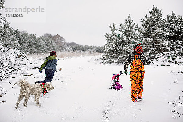 Verspielte Familie genießt auf schneebedecktem Feld gegen den Himmel