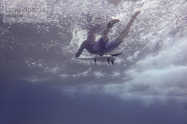 Unter Wasser surfender Mann in voller Länge im Meer