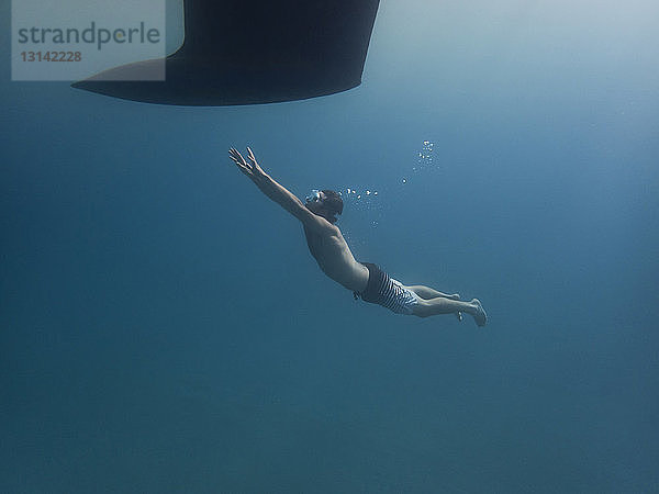 Mann schwimmt in voller Länge auf Kiel unter Wasser zu