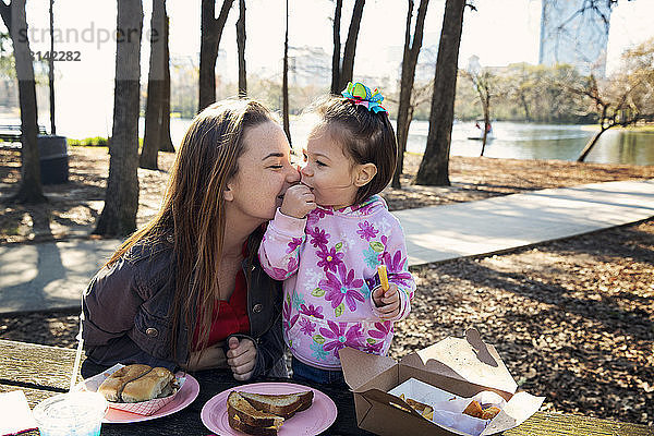 Mutter und Tochter beim Essen am Tisch im Park