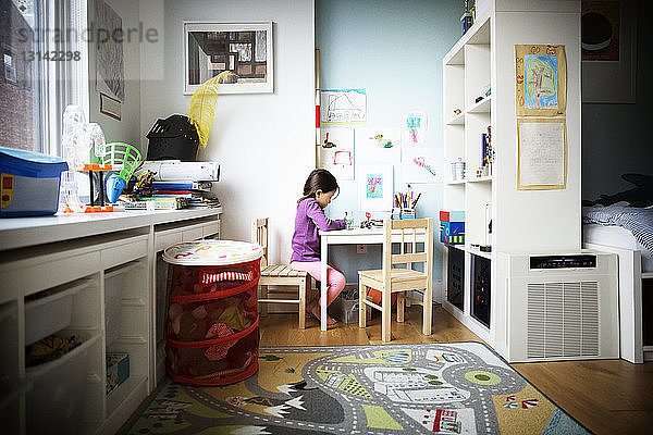 Mädchen lernt auf dem Tisch im Schlafzimmer