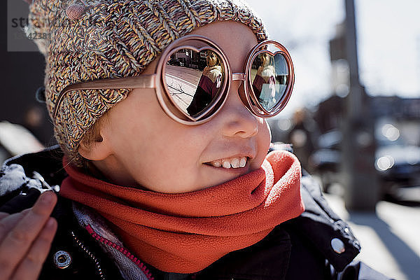 Lächelndes Mädchen mit Sonnenbrille und warmer Kleidung