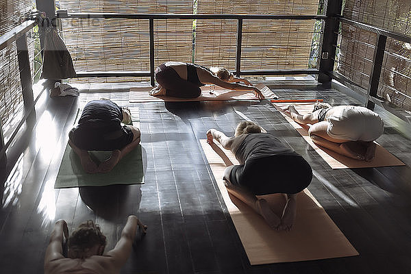 Schrägansicht von Frauen  die im Yogastudio die Pose eines Kindes üben