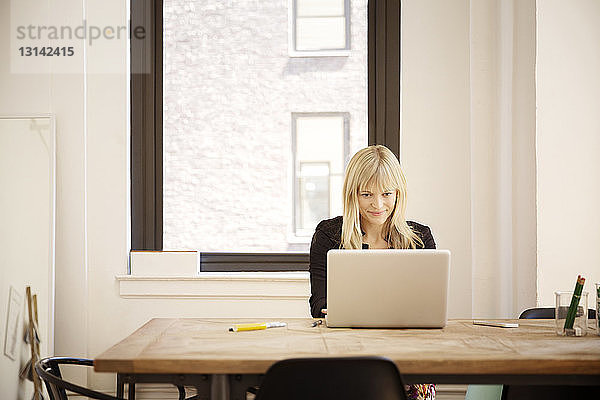 Schöne Geschäftsfrau mit Laptop am Schreibtisch im Büro