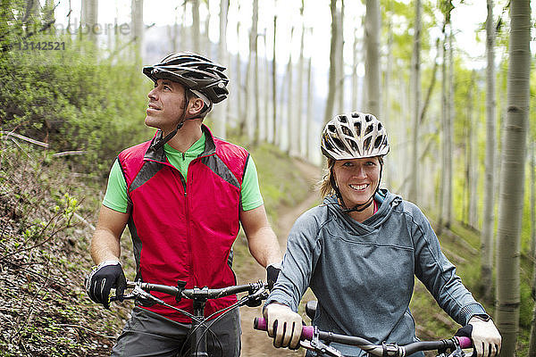 Porträt einer Radfahrerin  die im Wald bei einem Freund mit Fahrrad steht