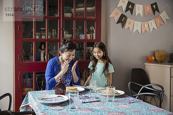 Überraschte Mutter schaut auf Pfannkuchen  die ihre Tochter zum Geburtstag gemacht hat