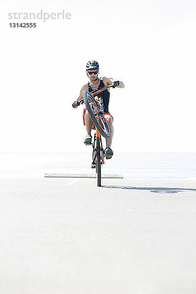 Mann führt Stunt mit Fahrrad aus - sonniger Tag