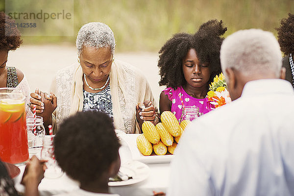 Familie betet gemeinsam am Frühstückstisch