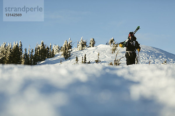 Oberflächenebenenbild eines Mannes mit Himmel  der auf einem schneebedeckten Berg gegen den Himmel läuft