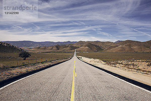 Landstraße führt zu den Bergen im Death Valley National Park gegen den Himmel