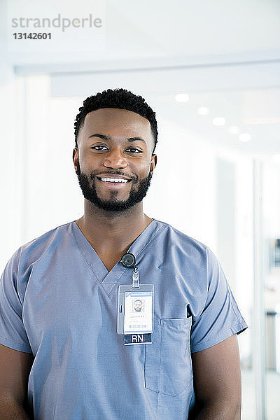 Porträt eines lächelnden Arztes  der im Krankenhauskorridor steht