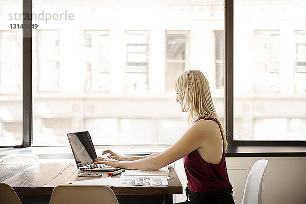 Seitenansicht einer Geschäftsfrau mit Laptop im Kreativbüro