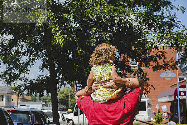 Rückansicht eines Mannes mit Tochter beim Spaziergang in der Stadt