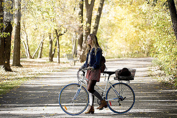 Frau mit Fahrrad schaut weg  während sie auf der Straße steht