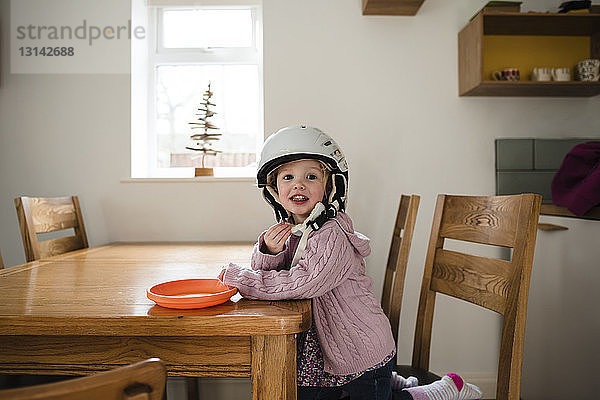 Porträt eines Mädchens mit Helm beim Essen am heimischen Tisch